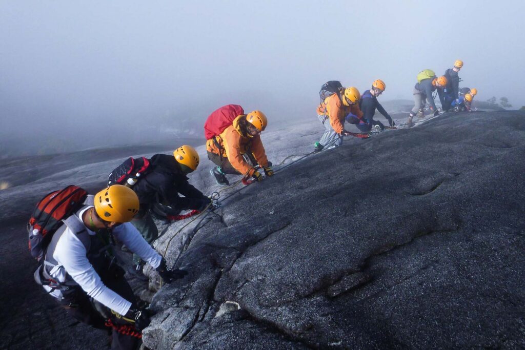 Kleine groep outdoor sporters die bij zonsopkomst hun gear voorbereiden in een bergachtig landschap.