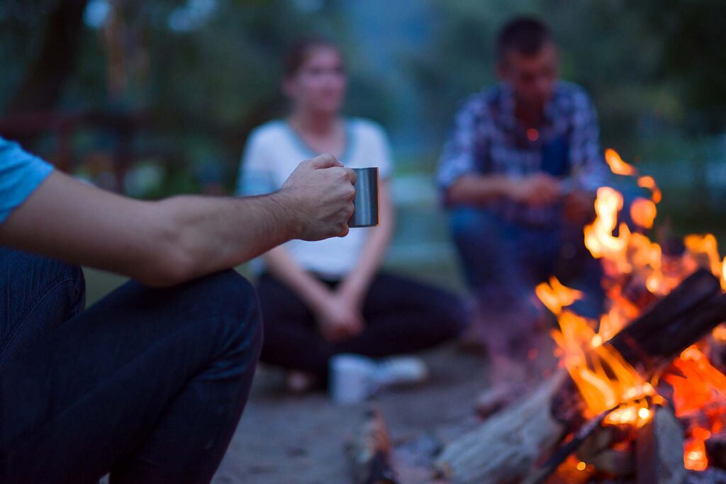 Eine Gruppe von Menschen sitzt während eines Outdoor-Abenteuers in der Natur gemeinsam um ein Lagerfeuer